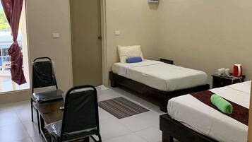 Habitación de hotel con dos camas, un escritorio, una silla, aire acondicionado y una ventana con cortinas.