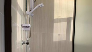 A bathroom with a glass shower enclosure, a handheld showerhead, and a wall-mounted faucet. - Bay View Barbers Lodge (Savusavu)