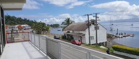 A balcony with a view of a coastal area, including a building labeled "COLD BEER" and several boats on the water.