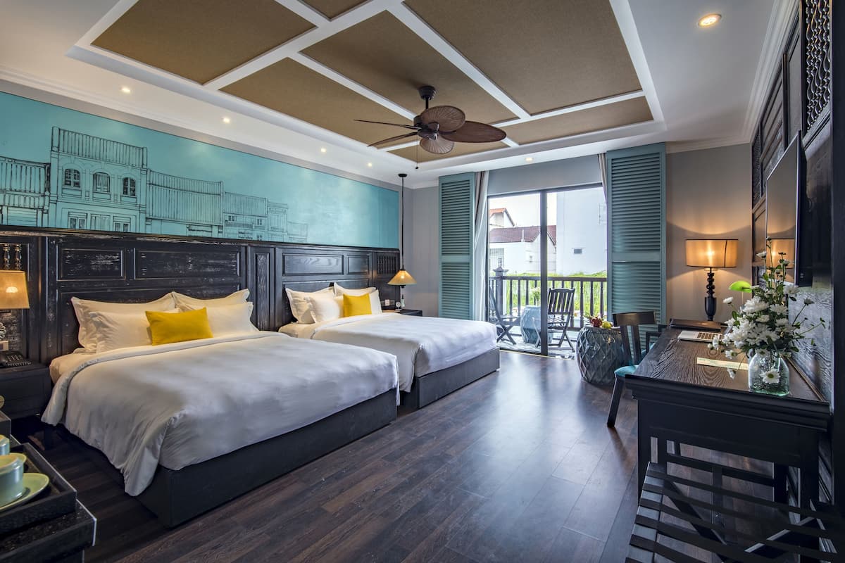 Ein Hotelzimmer mit zwei Betten, einem Esstisch und einem Balkon mit Blick.
