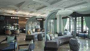 Un hall espacioso de diseño moderno, con una zona de estar curvada, chimenea y una cocina al fondo.