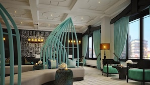 Un moderno vestíbulo de hotel con una zona de estar curva, una pared decorativa y grandes ventanales con cortinas.