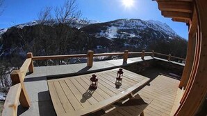 En träveranda med två lyktor, med utsikt över ett snötäckt bergskedja.