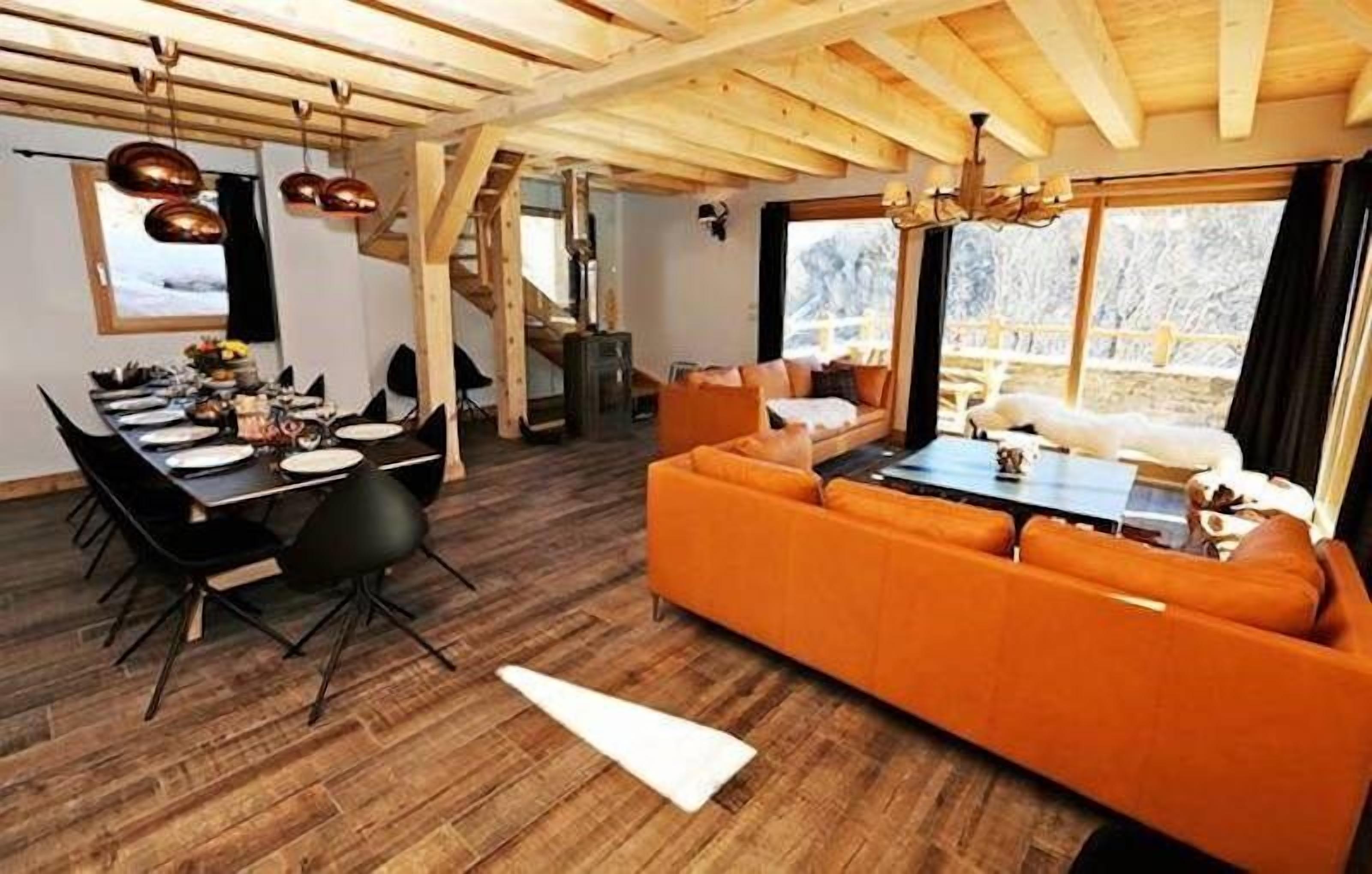 Un interno in legno con zona pranzo, divano e ampie finestre.