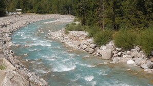 Un río serpentea por una zona montañosa con orillas rocosas y bosques densos.