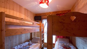 Una habitación con literas de madera, un televisor y una decoración con forma de corazón en la pared.