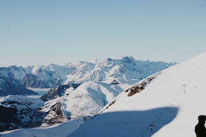 Paisagem montanhosa coberta de neve, com pistas de esqui e um teleférico.