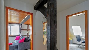 A spacious living area with a wooden staircase, a sofa with cushions, and a dining area with a table and chairs.