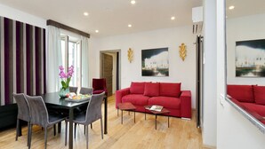 Ein modernes Wohnzimmer mit einem roten Sofa, einem Esstisch mit Stühlen und Kunstwerken an den Wänden.
