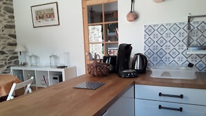 A kitchen with a wooden countertop, a coffee maker, a kettle, and a toaster. There is a window with a view of the outside, and a tiled backsplash. - House ALL COMFORT, NICE GARDEN, FEET IN THE WATER, DIRECT BEACH ACCESS (La Hague)