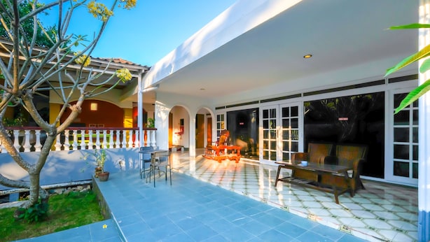 A covered patio area with outdoor seating, a small garden, and a view into the house. - OYO 1206 Lombok Guest House (Mataram)