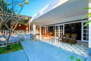 A covered patio area with outdoor seating, a small garden, and a view into the house. - OYO 1206 Lombok Guest House (Mataram)