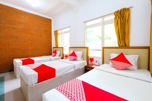A hotel room with two beds, a brick wall, and a window with yellow curtains. - OYO 1206 Lombok Guest House (Mataram)