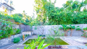 A courtyard with a small pond, stone steps, and various plants. - OYO 1206 Lombok Guest House (Mataram)