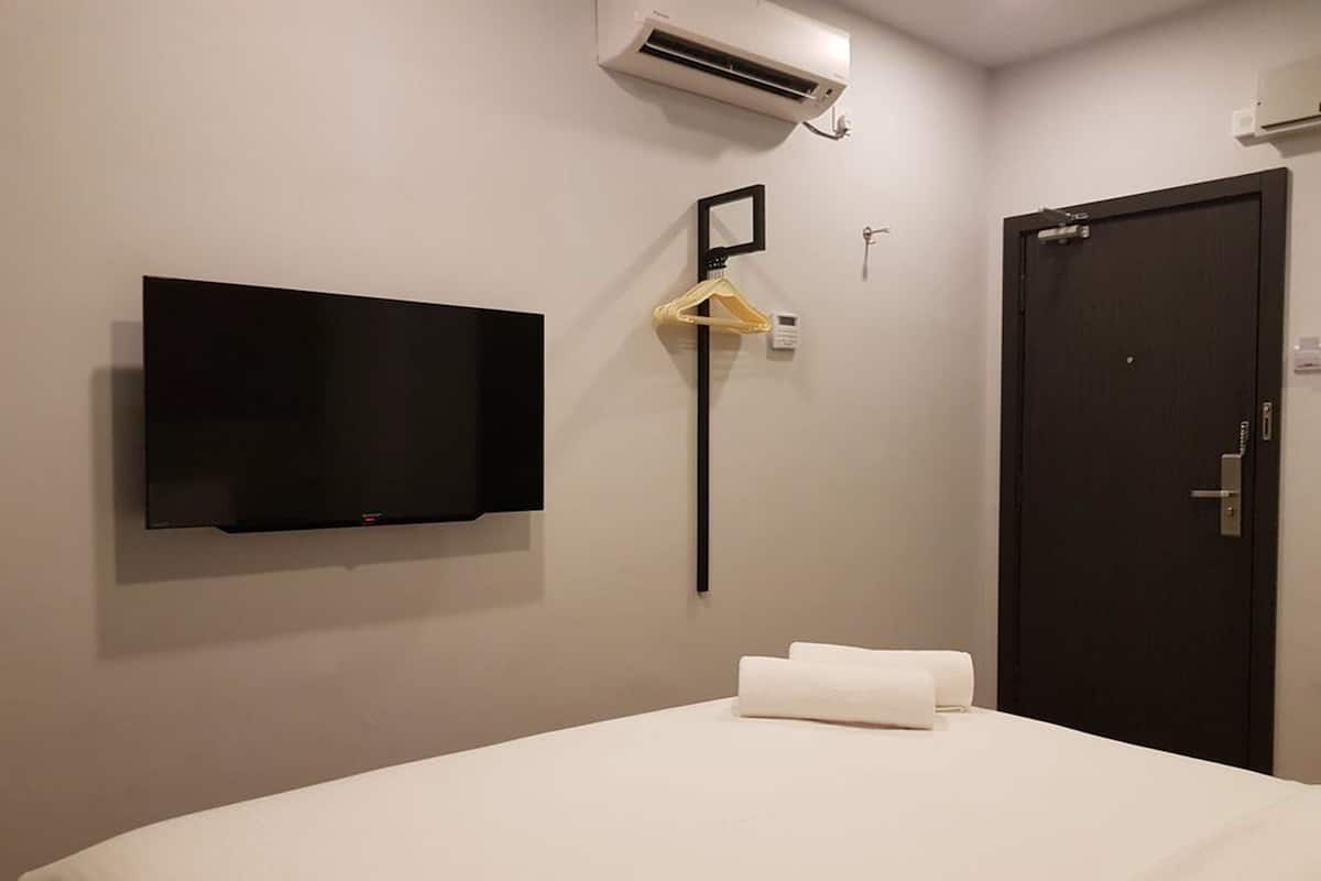 Een hotelkamer met een bed, een aan de muur bevestigde televisie, een deur en een airconditioning.