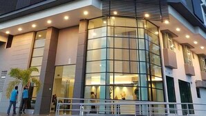 Um edifício moderno com fachada de vidro, escada e corrimão em primeiro plano.