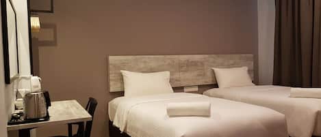 Una habitación de hotel con dos camas, una mesita con cafetera y una silla.