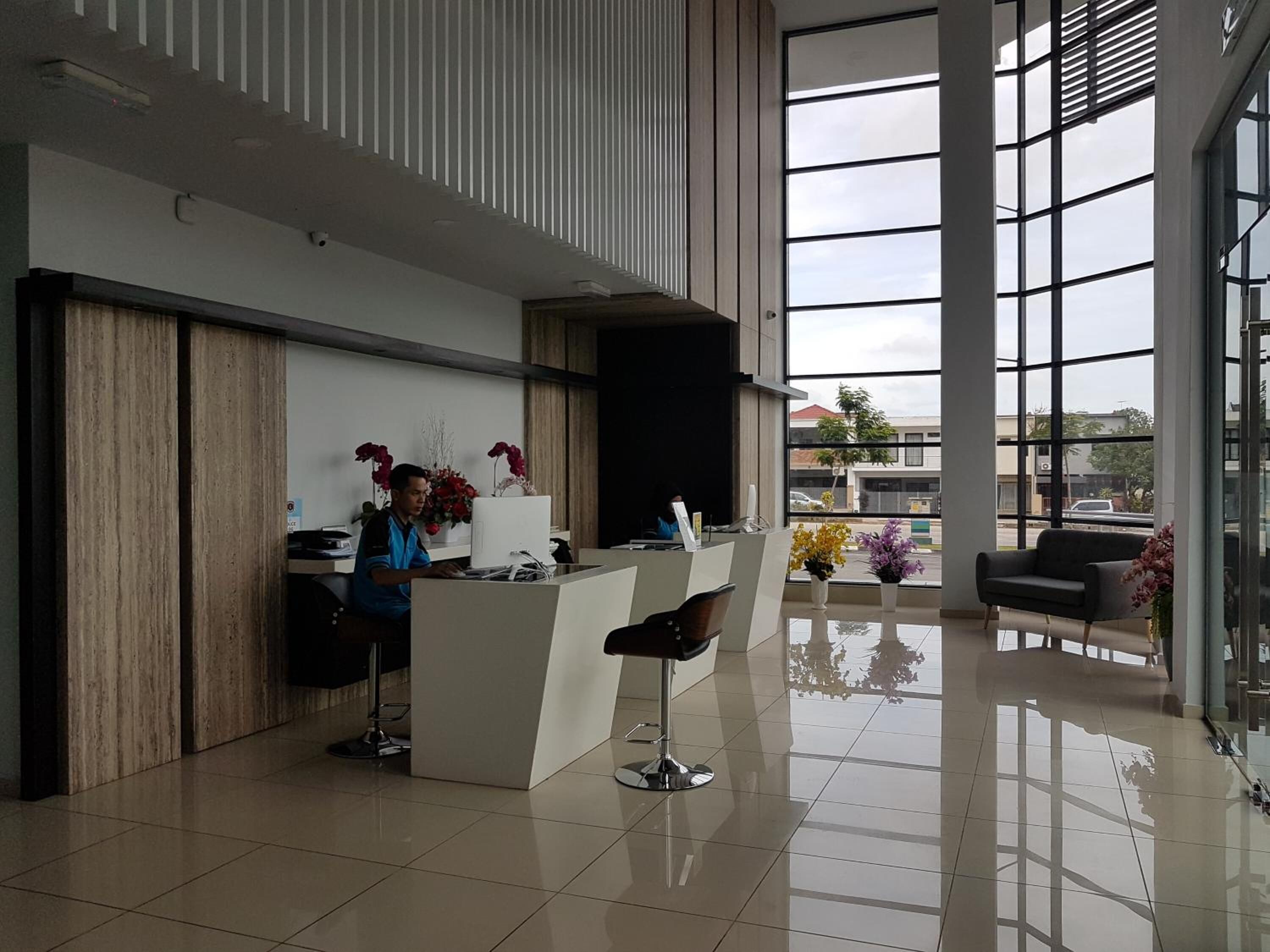 A modern reception area with a reception desk, two bar stools, and a large window offering a view of the street.