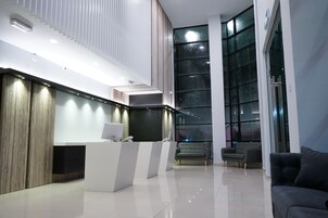 Un área de recepción moderna con un mostrador blanco, un sofá y un amplio ventanal con vistas al exterior.