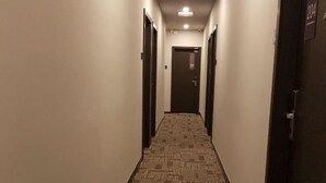 Um corredor estreito e revestido de carpete, com portas de ambos os lados, conduzindo a um aposento escuro no final.