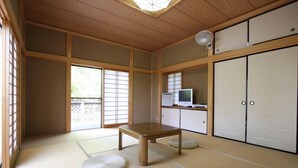 A traditional Japanese room with tatami flooring, a low wooden table, sliding doors, and a television on a cabinet. - Suitaikyou (Nasu)