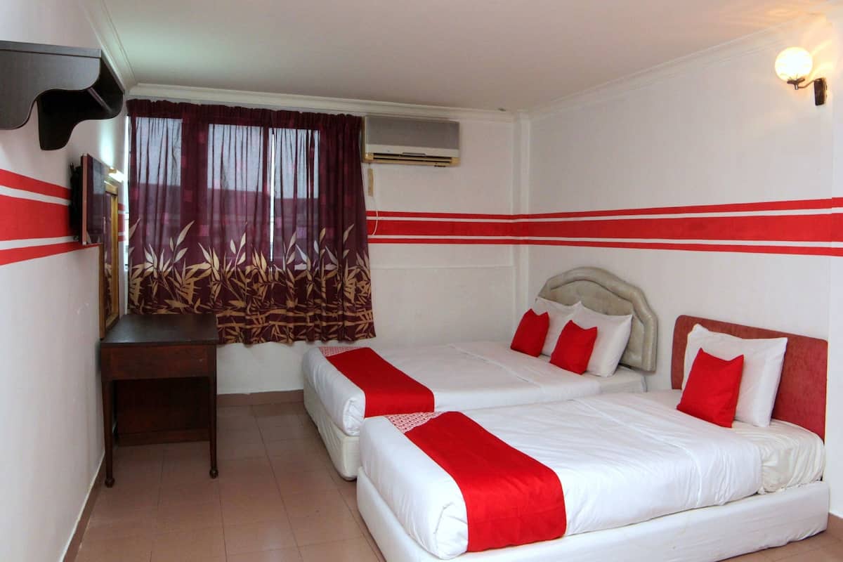 A hotel room with two beds, a desk, a TV, and a window with curtains.