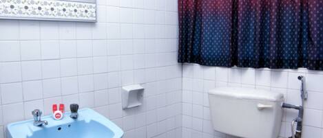 A bathroom with a blue sink, white toilet, and a shower with a hose.