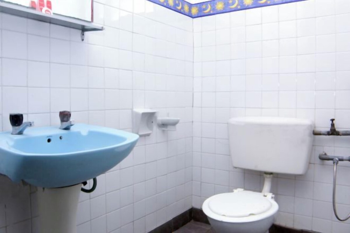 Un baño con un lavamanos azul, inodoro blanco y paredes con azulejos.