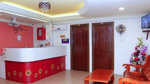 A reception area with a red counter, wooden doors, a ceiling fan, and a floral arrangement. - Super OYO 1173 Mandyrin Hotel (Sibu)