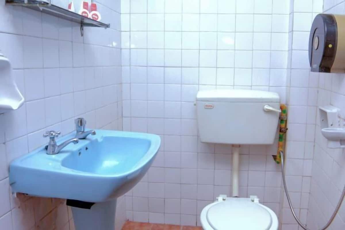 A bathroom with a blue sink, a toilet, and a paper towel dispenser.