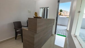 A reception area with a reception desk, a chair, and a decorative statue. - Hotel Tapovan Cottage (Narendranagar)
