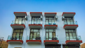 A multi-story building with balconies, air conditioning units, and a clear sky. - Hotel Tapovan Cottage (Narendranagar)
