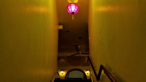 Un escalier muni d’une main courante, un plafond orné de trois lanternes illuminées et de petites lumières le long du mur.