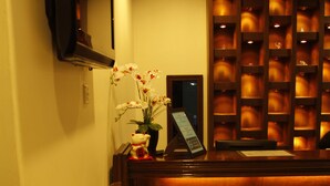 Un hall d’hôtel comprenant un comptoir d’accueil, un extincteur, une table avec des magazines et un téléviseur fixé au mur.