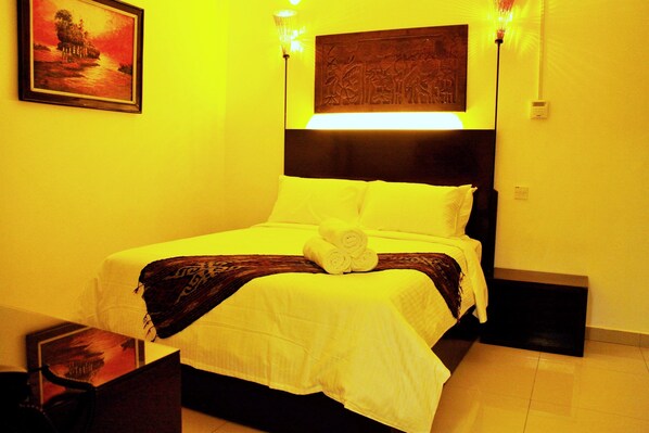 A hotel room with a bed, a painting on the wall, and a nightstand.