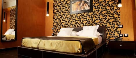 A hotel room with a bed, a large mirror, a wall-mounted picture, and a bedside table.