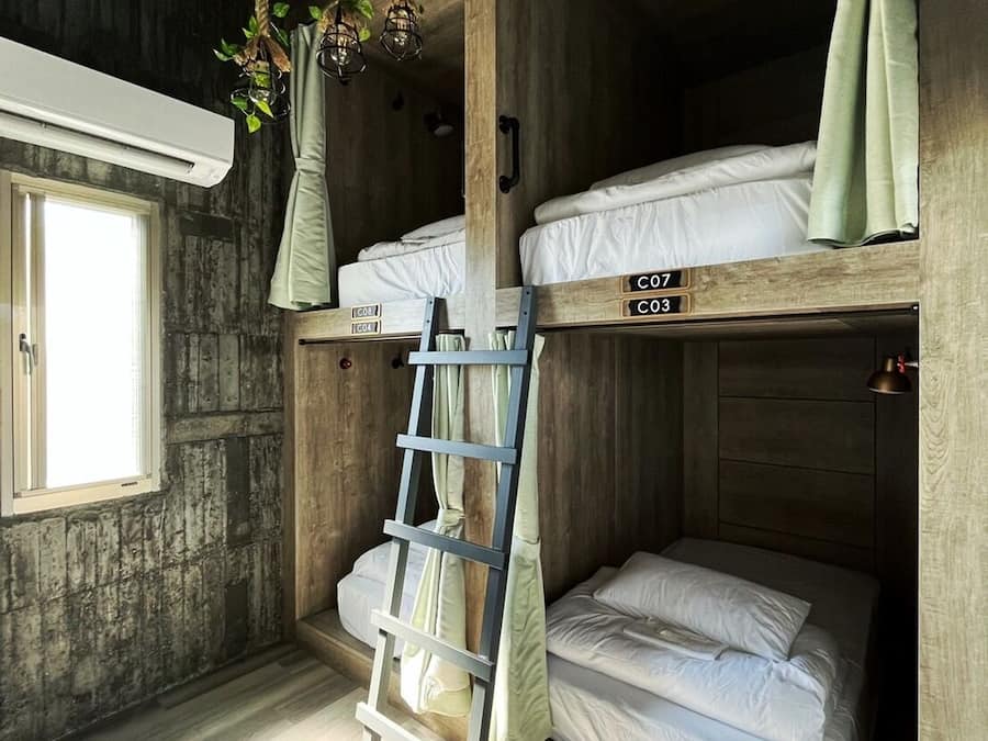 A bunk bed room with wooden walls, a ladder, and a window.