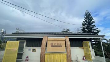 A building with a wooden signboard, a yellow gate, and a fire extinguisher.