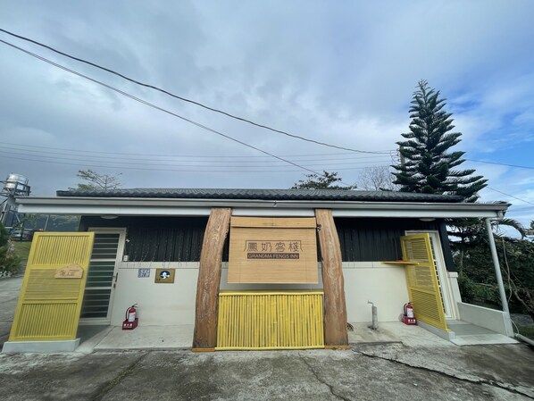 A building with a wooden signboard, a yellow gate, and a fire extinguisher.