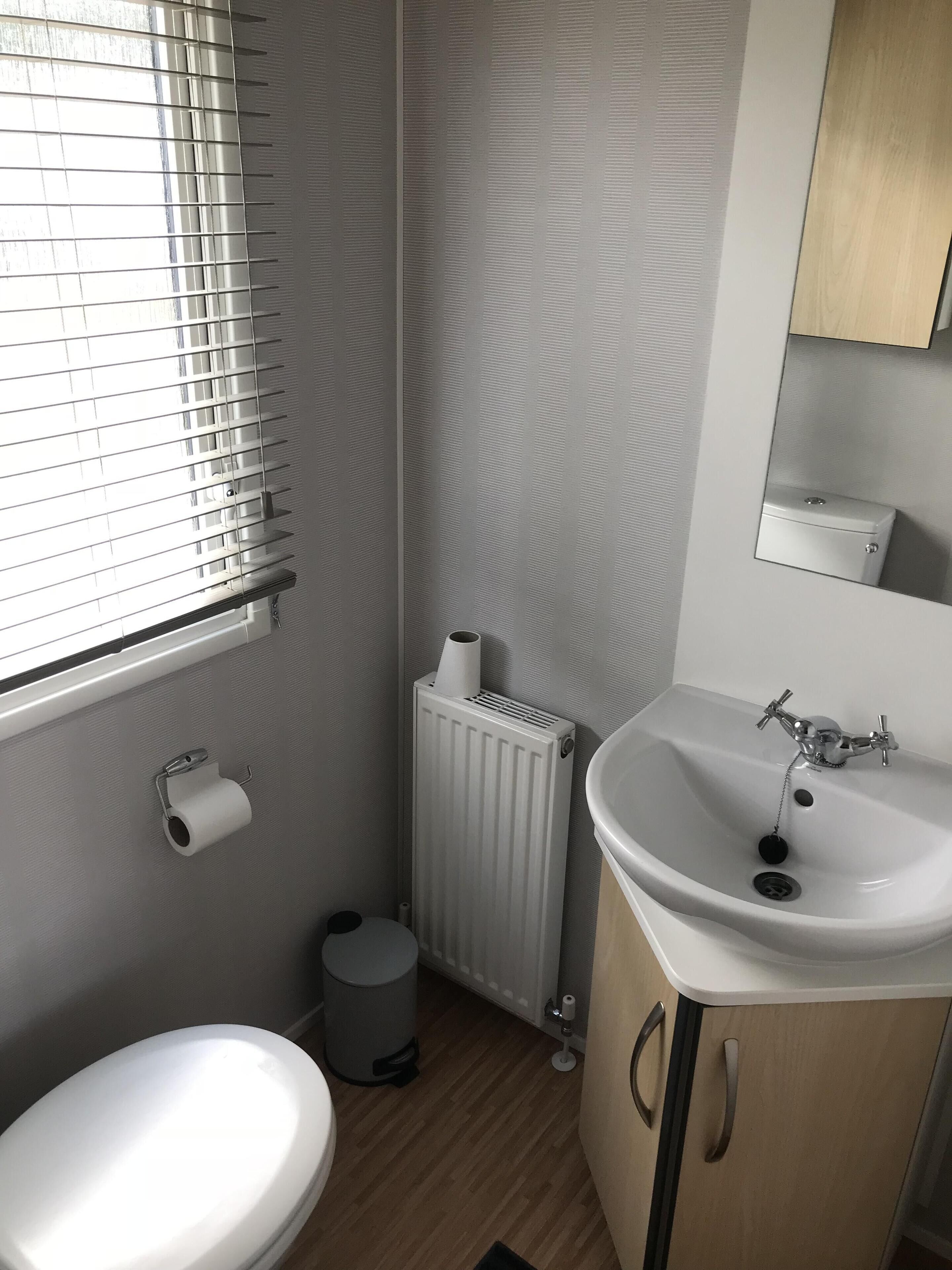 A small bathroom with a toilet, sink, and radiator.