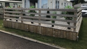 A mobile home with a wooden deck and potted plants. - 2 bedroom modern caravan in Ladybank, 20 minutes to St Andrews (Ladybank)