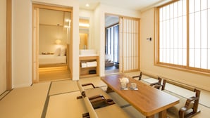 A traditional Japanese room with tatami flooring, a wooden table with cushions, and sliding doors. - Tomonoya Ryokan (Geoje)