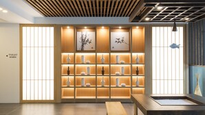 A modern interior with a wooden bench, a tea station, and a wall with framed artwork. - Tomonoya Ryokan (Geoje)