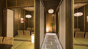 A traditional Japanese room with tatami flooring, wooden sliding doors, and a central pillar with a hanging light fixture. - Tomonoya Ryokan (Geoje)