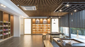 A modern interior with wooden shelves, a tea station, and a view through large windows. - Tomonoya Ryokan (Geoje)