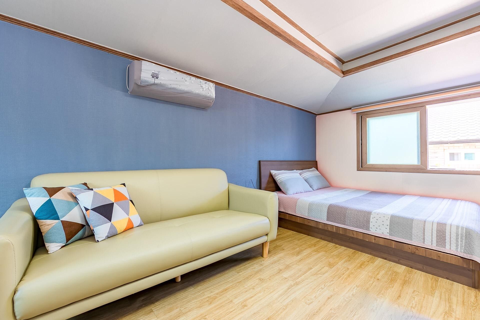 Una habitación con sofá, cama, ventana y aire acondicionado.