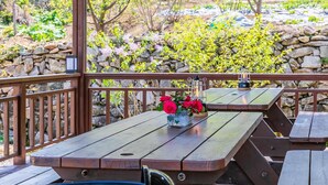 Una terraza de madera con mesas de picnic y una piscina pequeña.