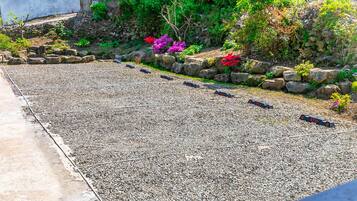 Um jardim com caminho de cascalho, muros de pedra e diversas plantas.