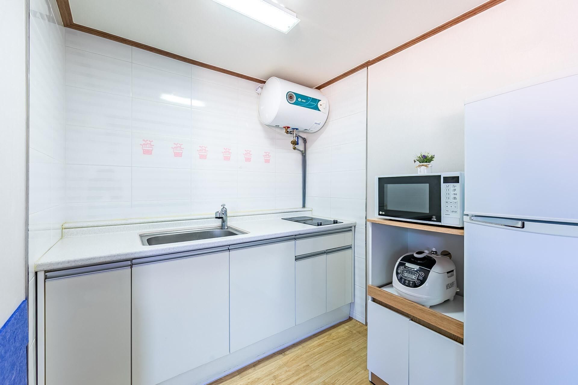 Une cuisine moderne avec des armoires blanches, un évier en acier inoxydable, un four à micro-ondes et un four encastré.