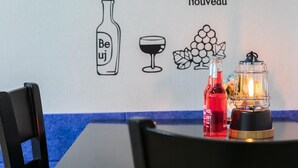 Una mesa con una botella de vino Beaujolais Nouveau, una copa de vino y un farol.